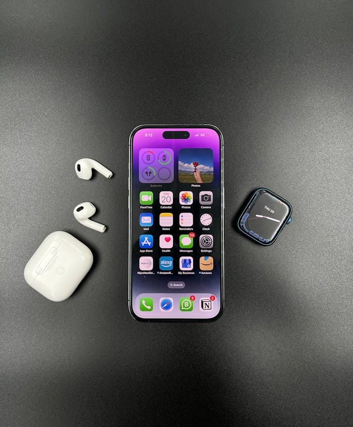 A sleek black setup featuring an iPhone, AirPods, and a smartwatch, showcasing modern technology.